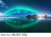 Aurora. Northern lights in Lofoten islands, Norway. Starry blue sky with polar lights. Night winter landscape with aurora, sea with sky reflection, beach, mountains, city lights. Green aurora borealis. Aurora. Nothern lights in Lofoten islands, Norway. Стоковое фото, агентство Ingram Publishing / Фотобанк Лори