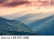Colorful landscape with Himalayan mountains, beautiful hills with green meadows, forest, orange sky with clouds and yellow sunlight at sunset in summer in Nepal. Mountain valley. Travel in Himalayas. Стоковое фото, агентство Ingram Publishing / Фотобанк Лори