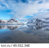 Sandy beach with beautiful reflection in water, Lofoten islands, Norway. Landscape with snowy mountains, sea, blue sky with clouds reflected in water in winter. Nature background with rocks and coast. Стоковое фото, агентство Ingram Publishing / Фотобанк Лори