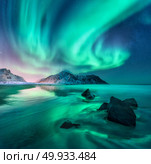 Aurora. Northern lights in Lofoten islands, Norway. Sky with polar lights, stars. Night winter landscape with aurora, sea with sky reflection, stones, sandy beach and mountains. Green aurora borealis. Aurora. Nothern lights in Lofoten islands, Norway. Стоковое фото, агентство Ingram Publishing / Фотобанк Лори