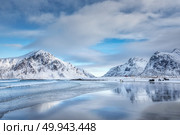 Snowy mountains and blue sky with clouds reflected in water in winter. Arctic sandy beach in Lofoten islands, Norway. Landscape with rocks, sea, people in cloudy day. Nature background. Nordic coast. Стоковое фото, агентство Ingram Publishing / Фотобанк Лори