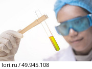 Chemical laboratory scene: attractive young PhD student scientist observing the indicator color shift in the glass tube. Стоковое фото, агентство Ingram Publishing / Фотобанк Лори