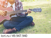 Young hipster man practiced guitar in the park,happy and enjoy p. Young hipster man practiced guitar in the park,happy and enjoy playing guitar. Стоковое фото, агентство Ingram Publishing / Фотобанк Лори