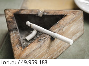 Black wood ashtray with cigarette stubs in closeup. Стоковое фото, агентство Ingram Publishing / Фотобанк Лори
