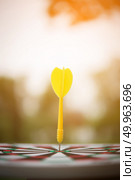 Yellow dart arrow hitting in the center of dartboard. Стоковое фото, агентство Ingram Publishing / Фотобанк Лори