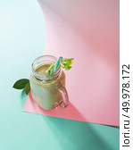 Vegetarian healthy smoothies from green vegetables with green leaves and plastic straw in a glass bowl on duotone pink green paper background. Pink paper twisted in any shape.. Green smoothie from green organic vegetables with asparagus and celery in a glass bowl on duotone pink green paper background. Стоковое фото, агентство Ingram Publishing / Фотобанк Лори