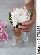 Cripsy waffle cup of a delicate white pion in a glass cup with gerls hand on a gray marble table.. A woman hand holds a waffle cup with a delicate white pion in a glass cup on a gray marble table. Стоковое фото, агентство Ingram Publishing / Фотобанк Лори
