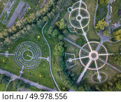 Aerial view of a natural labyrinth in the Botanical garden. Photo from the drone in the evening in summer.. Birds eye view from the drone to a Garden labyrinth and park alleys of the round form in the park. Стоковое фото, агентство Ingram Publishing / Фотобанк Лори