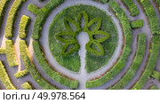 Aerial view from the drone to park labyrinth of round shape with bushes in the garden at sunset in a summer day. Topiary art.. Aerial view of the symmetrical round form of the labyrinth from the cut bushes. Photo from the drone. Стоковое фото, агентство Ingram Publishing / Фотобанк Лори
