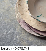 Traditional souvenir porcelain handmade colorful plate and bowl on a gray concrete background with place under text. Flat lay. Handcrafted clay empty bowls and plates covered with glazed on a gray concrete background. Стоковое фото, агентство Ingram Publishing / Фотобанк Лори