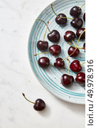 Summer tasty fruits cherries on a white plate. Sweet berries on a gray marble background. Concept of clean organic eating.. Sweet berries red ripe on blue plate on gray background with place for text. Flat lay. Стоковое фото, агентство Ingram Publishing / Фотобанк Лори