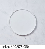 Top view of porcelain plate handmade. Ceramic glazed plate is empty on a gray background. Can be used for display or montage your products.. Decorative ceramic white plate, covered with glazed on a gray background. Traditional ceramic handcrafted. Flat lay. Стоковое фото, агентство Ingram Publishing / Фотобанк Лори
