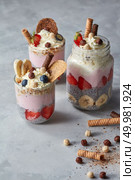 A healthy dessert made of chia seeds with yoghurt, strawberries, biscuits and bananas in glasses on a concrete background. Free space for text.. Chia pudding with yoghurt, honey, strawberry and banana on pastel concrete background. Стоковое фото, агентство Ingram Publishing / Фотобанк Лори