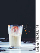 Delicious biscuit in a glass of milk and spilled milk on a black wooden background with copy space. Traditional Christmas treat for Santa - homemade oatmeal cookies.. Homemade peanut cake fall to a glass of milk with splash on a black wooden table. Стоковое фото, агентство Ingram Publishing / Фотобанк Лори