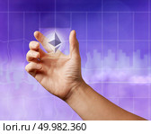 Business men holding a transparent screen with an icon of etereum on the ultraviolet background of the city. Business, Blockchain technology.. Icon of etereum on a transparent digital screen on the ultraviolet background of the city. Стоковое фото, агентство Ingram Publishing / Фотобанк Лори