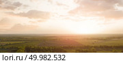 Panoramic view from the drone, aerial photography of landscape with agricultural fields prepared for sowing crops on the background of the cloudy sky at sunset in green and black colors.. Aerial view from the drone, a bird’s eye view of abstract geometric forms of agricultural fields with a dirt road through them in the summer evening at sunset. Стоковое фото, агентство Ingram Publishing / Фотобанк Лори
