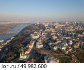 Kiev, Ukraine - April 7, 2018: Beautiful landscape view of the city with the Dnieper River and the pedestrian bridge. Aerial view to the St. Andrew’s Church on Podol. Drone photography. Kiev, Ukraine - April 7, 2018: Aerial view of Saint Andrew church. The old town of Kiev, the Podile district. Редакционное фото, агентство Ingram Publishing / Фотобанк Лори