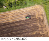 Aerial view from the drone of the field after harvest. The tractor plows the field, preparing the soil for agricultural work.. Plowing the ground after harvesting on the field in the autumn time. Top view. Стоковое фото, агентство Ingram Publishing / Фотобанк Лори