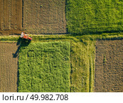 Abstract geometric forms of agricultural fields with different crops and soil without crop sowing, separated by road and tractor on it, in green and black colors. A bird’s eye view from the drone.. Aerial view from the drone, a bird’s eye view of agricultural fields with a road through and a tractor on it in the spring evening at sunset. Стоковое фото, агентство Ingram Publishing / Фотобанк Лори