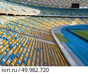 KIEV, UKRAINE - July 19, 2018. National Sports Complex Olimpiysky, aerial view to a football field, tribune and treadmills of stadium in a summer time before match. Aerial view from drone. KYIV, UKRAINE - July 19, 2018. The inside part of the Olympic sports complex with a football field, stands and treadmills. Редакционное фото, агентство Ingram Publishing / Фотобанк Лори