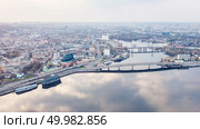 Aerial panoramic view from the drone on the central historical part of the city Kiyv and the district of Podol with Rybalskiy Island, churches, the ships, river docks and Havana bridge. Reflection of sunset and cloudy sky in the Dnieper River.. The panoramic bird’s eye view shooting from drone of the Podol district, the right bank of the Dnieper River and Rybalskiy Island in Kiev, Ukraine at summer sunset on the background of the cloudy sky. Стоковое фото, агентство Ingram Publishing / Фотобанк Лори