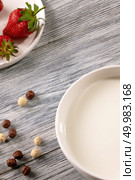 Chocolate and white grain balls with strawberries and of milk plate on a gray wooden table with copy space. Top view. Ripe strawberries, cereal balls and a plate of milk on a gray wooden table. Top view. Стоковое фото, агентство Ingram Publishing / Фотобанк Лори