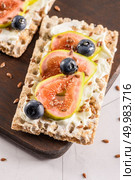 Canape or crostini with multigrain  crispread with cream cheese and fresh fig slices on a wooden board. Delicious appetizer ideal as an aperitif. Стоковое фото, агентство Ingram Publishing / Фотобанк Лори