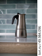Beautiful blue kitchen in an apartment with a stainless geyser coffee maker on the induction panel. A stainless geyser coffee machine is on the electric stove. Стоковое фото, агентство Ingram Publishing / Фотобанк Лори