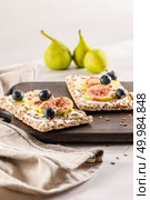 Canape or crostini with multigrain  crispread with cream cheese and fresh fig slices on a wooden board. Delicious appetizer ideal as an aperitif. Стоковое фото, агентство Ingram Publishing / Фотобанк Лори