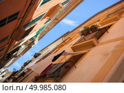 High wall of old four-store houses with bluish shutters above curve empty side-street, washing linen on ropes. Spain.. View on Palma de Mallorca. Стоковое фото, агентство Ingram Publishing / Фотобанк Лори