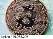 Close up golden bitcoin metallic coin over paper money euro banknotes. Bitcoin cryptocurrency. Business concept and future financial technology concept. Close up golden bitcoin on Euro background. Bitcoin cryptocurrency. Стоковое фото, агентство Ingram Publishing / Фотобанк Лори