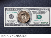 Gold coins bitcoin on a hundred dollar bill close the image of Franklin, on a dark background.. Gold coins bitcoin and one hundred dollars on a dark background. Стоковое фото, агентство Ingram Publishing / Фотобанк Лори