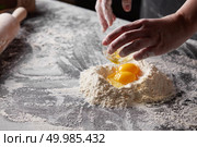 On a kitchen table a pile of flour with yolks, baker pours the squirrels into the flour. Step-by-step preparation of the dough. women’s hands is cooking dough for baking on a kitchen table. Стоковое фото, агентство Ingram Publishing / Фотобанк Лори