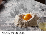 Two fresh yolks, a pile of flour and a plate of protein on the kitchen table. Ingredients for dough, step by step cooking. Two yolks and flour on the kitchen table. Ingredients for dough. Стоковое фото, агентство Ingram Publishing / Фотобанк Лори