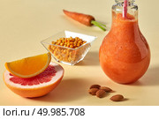 Dietary drink with carrots, grapefruit, orange, sea buckthorn and almonds in a glass on a yellow paper background. Healthy detox smoothies. Citrus vegetable smoothies with almonds and sea-buckthorn in a glass on a yellow paper background. Стоковое фото, агентство Ingram Publishing / Фотобанк Лори
