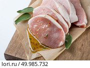 Raw meat. Pork escalope with sause made of honey and herbs with green sage leaves on wooden board against white background. Top view. raw pork escalope with sause made of honey and herbs. Стоковое фото, агентство Ingram Publishing / Фотобанк Лори