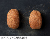 Two delicious buns isolated on black background. Two buns are represented separately, but parallely. Different kinds of bread on background. Bread concept.. Different kinds of bread on background. Стоковое фото, агентство Ingram Publishing / Фотобанк Лори