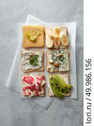 Party starter or appetizer - flat lay composition. Top view of different kinds of colorful sandwiches on white chalkboard background. Food industry concept.. Different kinds of sandwiches. Стоковое фото, агентство Ingram Publishing / Фотобанк Лори