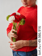 Young woman holds in hands, colorful flowers of ranunculus on gray background. As a gift for the holiday. A fresh bouquet of flowers Ranunculus in the hands of a woman on a gray background. Card. Стоковое фото, агентство Ingram Publishing / Фотобанк Лори