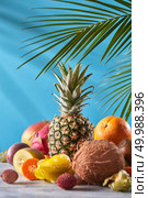 Dragon fruit, mango, passion fruit, coconut, pineapple, carambola, kumquat on a blue background with copy space. Group of exotic tropical fruits. Vegetarian healthy concept.. Exotic mix from ripe fresh fruits - pineaple, dragon fruit, mango, coconut, kiwi, carambola, litchi on a gray stone table on a blue. Стоковое фото, агентство Ingram Publishing / Фотобанк Лори