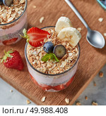 Healthy breakfast with homemde granola, yogurt, slices of strawberries, banana, blueberries, oat flaks, chia seeds on a wooden board. Concept of healthy dieting food.. The glass with oat flakes, banana fruits, strawberries, fresh smoothie, chia seeds on a wooden board. Стоковое фото, агентство Ingram Publishing / Фотобанк Лори