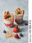 Fresh natural organic ingredients for cooking healthy breakfast -homemade granola, halves of strawberries, chia seeds, blueberries and yogurt in a glasses on a gray stone table, place for text.. Prepered homemade breakfast from healthy natural ingredients - oat flakes, banana slices, yogurt on a gray concrete background. Стоковое фото, агентство Ingram Publishing / Фотобанк Лори