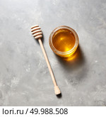 Sweet flower natural honey in a jar and wooden spoon on a gray concrete table, copy space. Top view. Jewish rosh hashanah holiday concept. Traditional useful sweetness.. Top view of glass jar with sweet meadow honey on a gray stone background. Jewish New Year healthy holiday . Стоковое фото, агентство Ingram Publishing / Фотобанк Лори