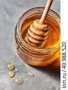 Wooden stick in a glass jar with aromatic natural organic honey on a gray marble table, place for text. Rosh hashanah jewish New Year holiday concept.. Close up of wooden honey stick in a glass pot with sweet organic dessert on a gray stone background, traditional useful sweetness. Стоковое фото, агентство Ingram Publishing / Фотобанк Лори