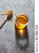 Sweet floral natural honey full a jar and wooden spoon on a gray concrete table, copy space., pure natural sweet goodness. Jewish rosh hashanah holiday concept.. Wooden stick on a spilled honey on the table and glass pot with natural meadow sweet dessert on a gray kitchen table. Pure natural sweet goodness. Стоковое фото, агентство Ingram Publishing / Фотобанк Лори