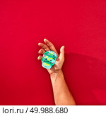Paper handmade craft skull Calaveras attributes of the Mexican holiday Calaca holds the hand of a man on a red background with space of text. Holiday Halloween. The hand of a man holds a handcraf paper skull Calaveras attributes of the Mexican holiday Calaca on a red background with space for text and reflection of shadows. Halloween. Flat lay. Стоковое фото, агентство Ingram Publishing / Фотобанк Лори
