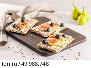 Canape or crostini with multigrain  crispread with cream cheese and fresh fig slices on a wooden board. Delicious appetizer ideal as an aperitif. Стоковое фото, агентство Ingram Publishing / Фотобанк Лори