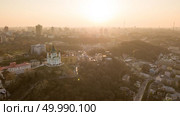 Sunset over Saint Andrew’s church and cityscape of Podol district in Kyiv, Ukraine. Dramatic skyline view at drone. Aerial top view of Saint Andrew’s church and cityscape of Podol district on sunset in city of Kiev , Ukraine. Стоковое фото, агентство Ingram Publishing / Фотобанк Лори