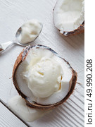 Ice cream in a half of coconut with a spoon On white wooden background. Delicious coconut ice cream. Стоковое фото, агентство Ingram Publishing / Фотобанк Лори