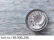 Porcelain gray bowls and plates on a gray wooden table with place for text. Colorful ceramic vintage handmade dishes. Flat lay. Decorative pottery - bowls, plates covered with glazed on a gray wooden background. Top view of traditional handcrafted. Стоковое фото, агентство Ingram Publishing / Фотобанк Лори